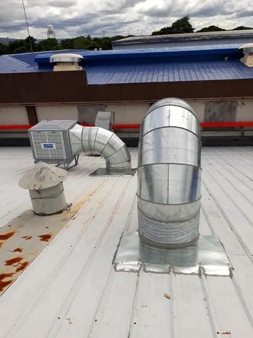 Close-up of industrial ducting and blower fan unit installed on a factory rooftop