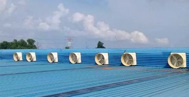 Aerial view of a blue metal factory roof with an industrial exhaust fan installed