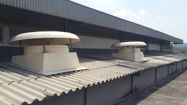 Row of circular industrial roof exhaust fans installed on a blue metal factory roof